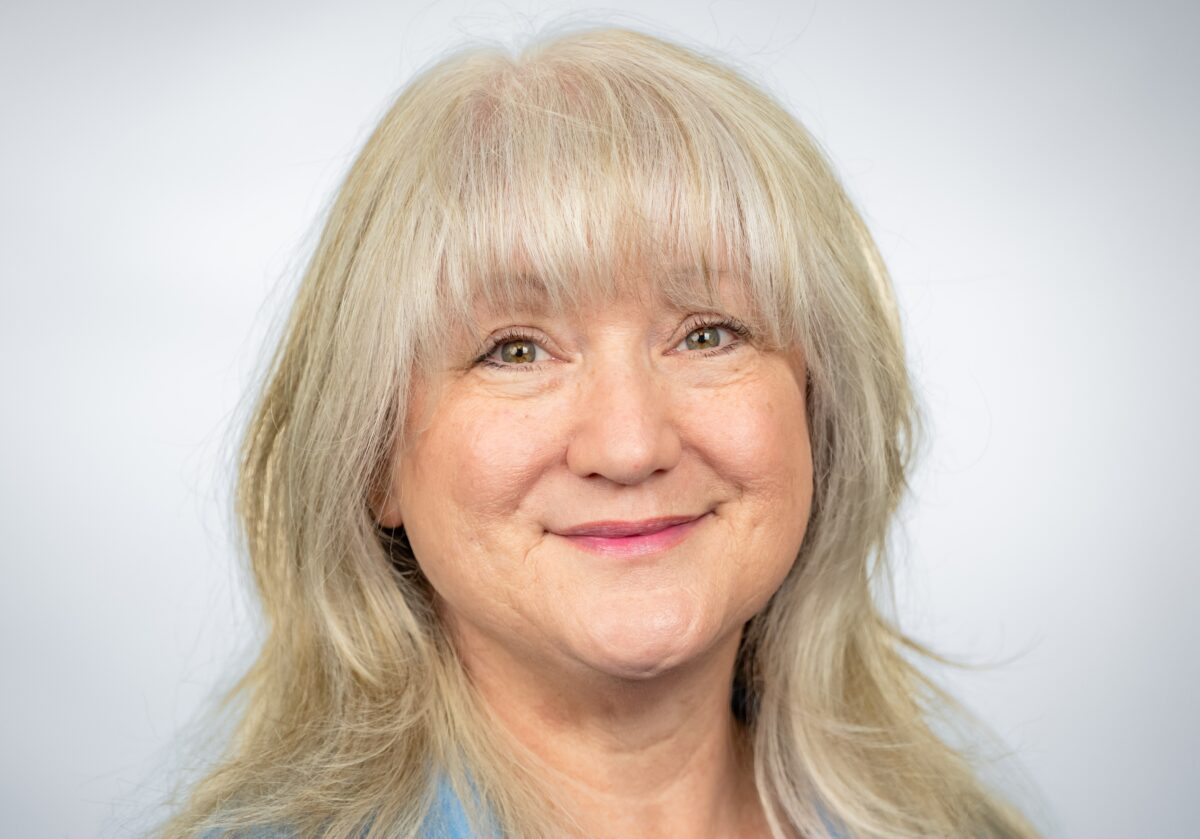 Professional photo of Kim Terrell with blue shirt and green background with navy overlay