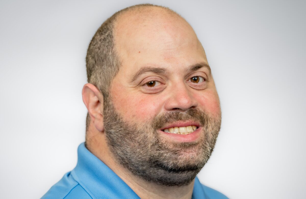 Professional photo of Mike for meet the team with blue shirt, green background and navy overlay