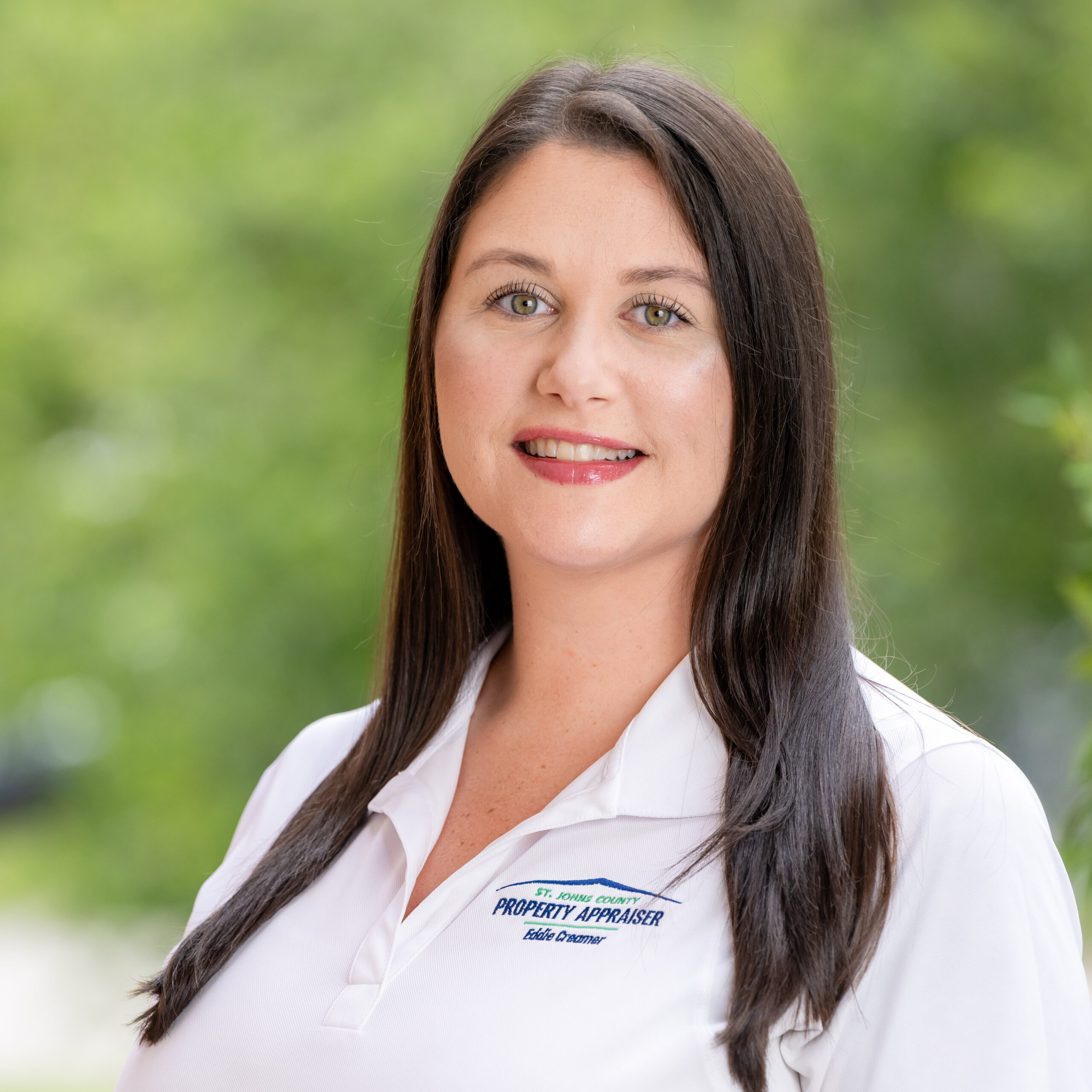 Photo of Brandi with white shirt and greenery in background