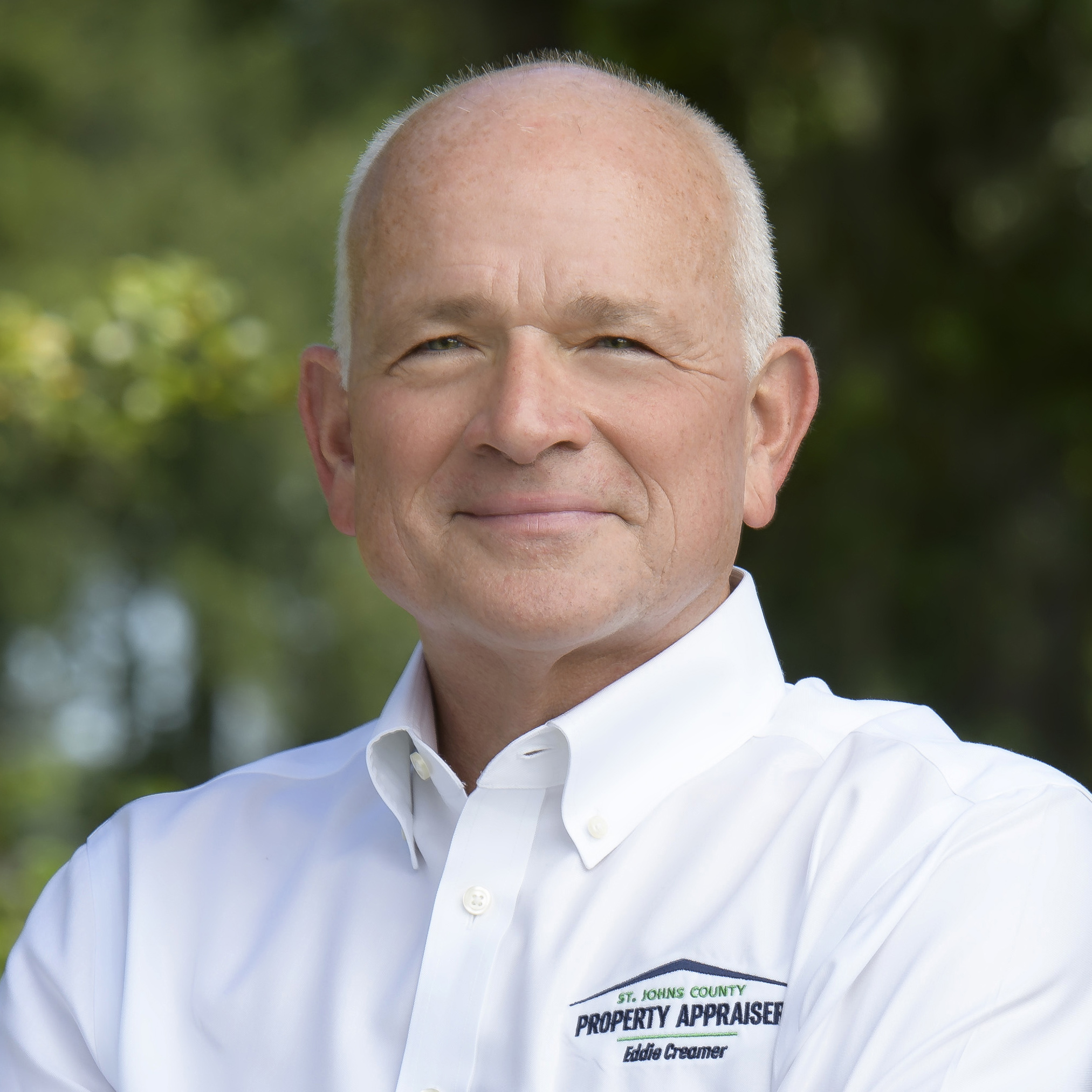 Photo of Eddie with white shirt and green tree trees in background