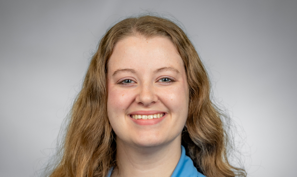 Rebecca is looking at the camera with blue shirt and gray background