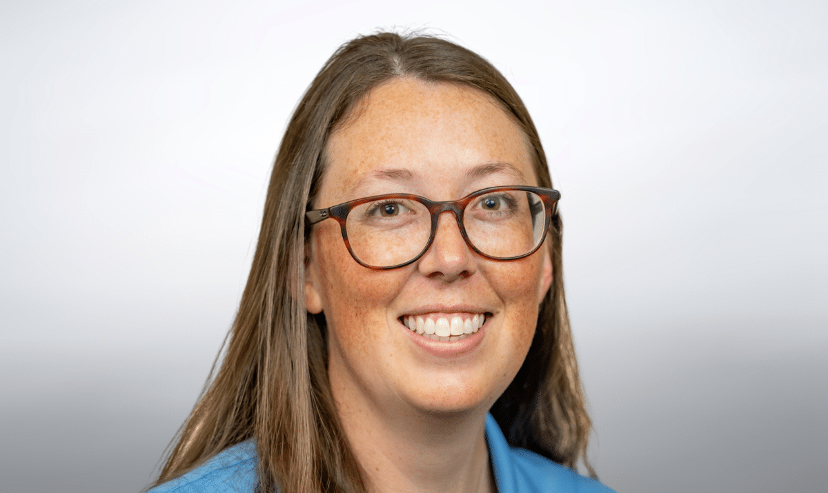 Professional photo of Sarah with blue shirt and gray background