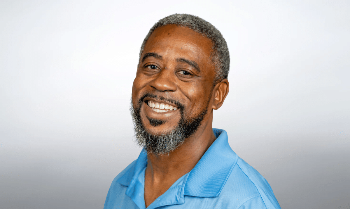 Professional photo of TJ with blue shirt and gray background